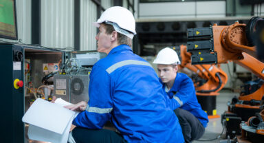 Factory employees with robot arm and computer