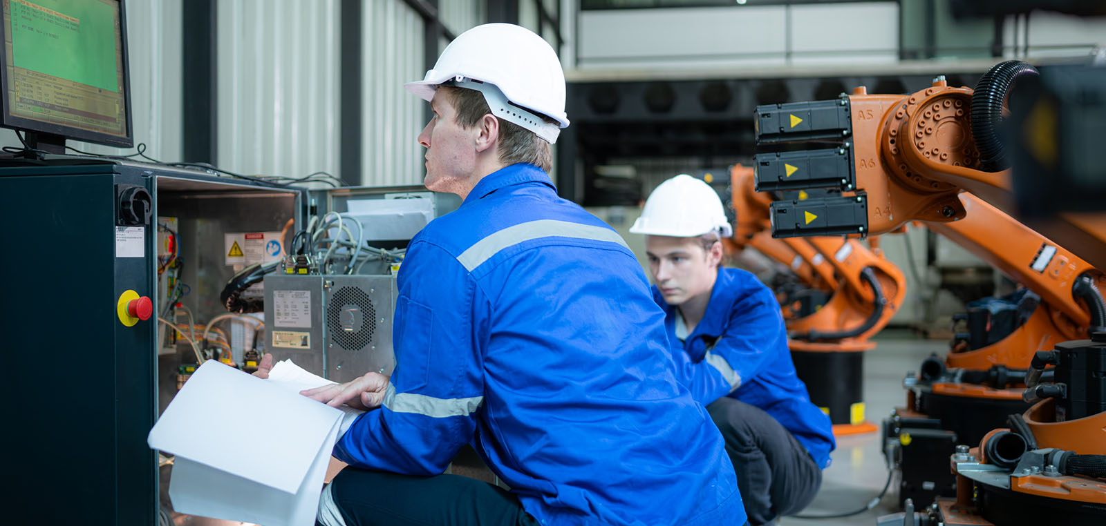 Factory employees with robot arm and computer